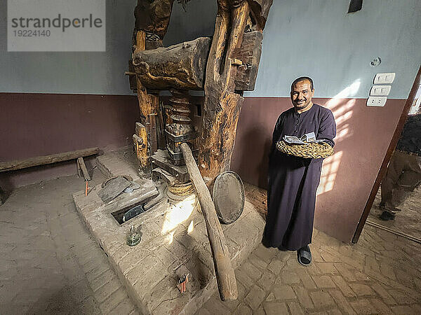Ein ägyptischer Mann an einer Weinpresse im Herzen der Stadt Dendera  Ägypten  Nordafrika  Afrika