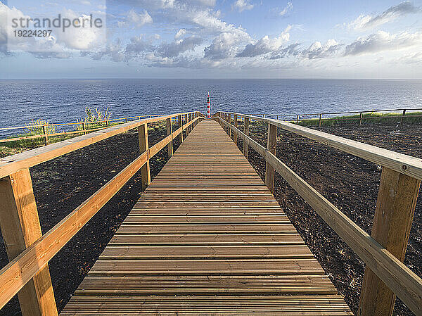 Leuchtturm Farolim dos Fenais da Ajuda mit einem symmetrischen Holzweg  der dorthin führt  Insel Sao Miguel  Azoren  Portugal  Atlantik  Europa