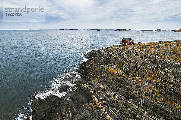 Einsames rotes Haus  umgeben vom Meer auf einer Klippe einer felsigen Insel  Bohuslän  Västra Götaland  Westschweden  Schweden  Skandinavien  Europa