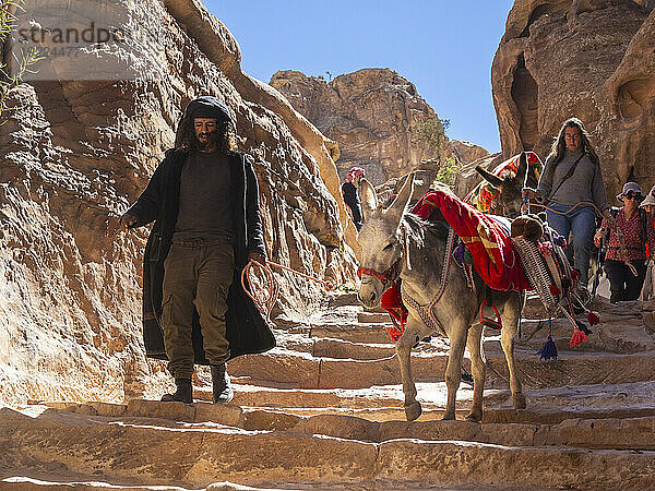 Esel  Führer und Touristen auf dem Weg zum Kloster Petra (Al Dayr)  Archäologischer Park Petra  UNESCO-Weltkulturerbe  eines der neuen sieben Weltwunder  Petra  Jordanien  Naher Osten