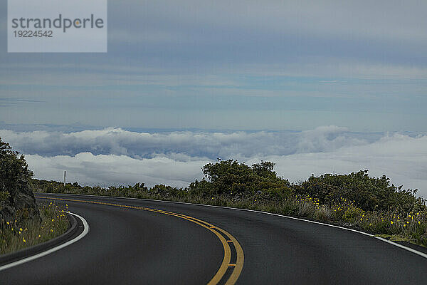 Nahaufnahme einer scharfen Kurve auf der asphaltierten Autobahn mit Blick von oben auf die Wolken am Berghang auf der Straße von Haleakala hinunter; Maui  Hawaii  Vereinigte Staaten von Amerika