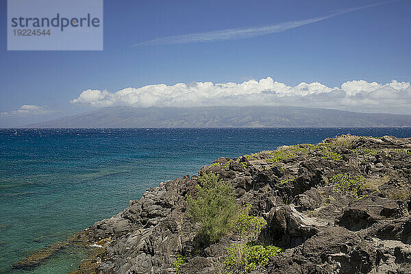 Blick auf das türkisfarbene Meer  den blauen Himmel und die Silhouetten der Berge von einem felsigen Ufer aus; Maui  Hawaii  Vereinigte Staaten von Amerika