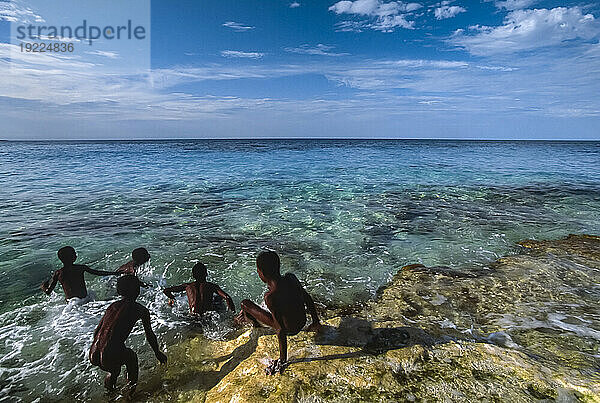 Kinder schwimmen entlang der felsigen Küste der Insel Great Exuma; Great Exuma Island  Bahamas