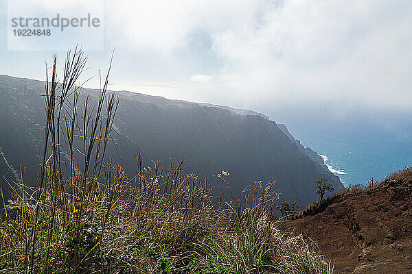 Malerische Aussicht auf die Bergklippen der Napali-Küste entlang des Kalalau Trail auf der hawaiianischen Insel Kauai mit Blick auf die nebligen Wolken über dem blauen Wasser des Pazifischen Ozeans; Kauai  Hawaii  Vereinigte Staaten von Amerika