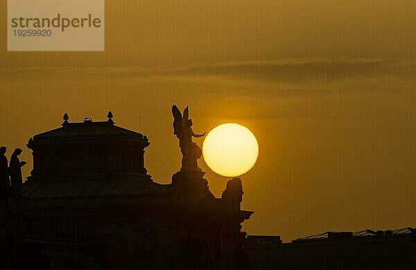 Sonnenuntergan in Dresden. Die Sonnenscheibe  durch den Saharastaub  besonders orange eingefäbt  geht hinter der Silhouette der Dresdner Altstadt unter