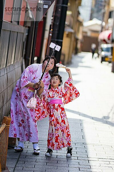 Eine junge Mutter und ihre Tochter machen ein Selfie in den Straßen von Kyoto an einem warmen Frühlingstag  Kyoto  Japan  Asien