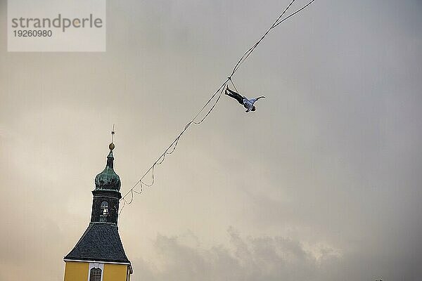 Highline- und Familienfest in Hohnstein Über den Dächern Hohnsteins und zwischen Sandsteinfelsen sind Highlines gespannt  über welche wagemutige Extremsportler balancieren. Ruben Langer beeindruckt mit Kunststücken auf einer Highline vom Kirchturm zur Burg Hohnstein.Sturz in die Sicherung