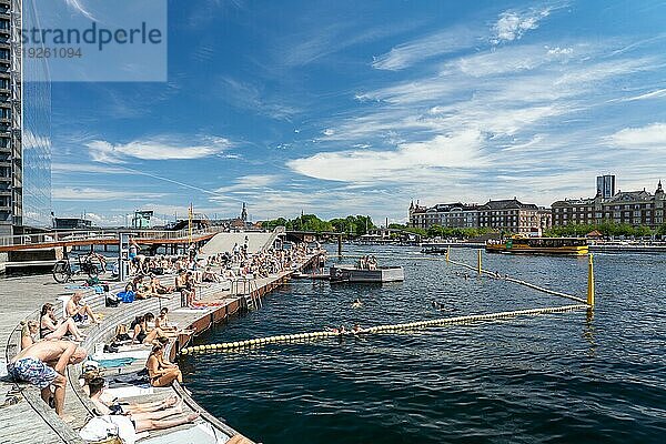 Kopenhagen  Dänemark  30. Juni 2022: Menschen genießen die Sonne an der Kalvebod Welle  einer Holzpromenade am Hafenufer  Europa