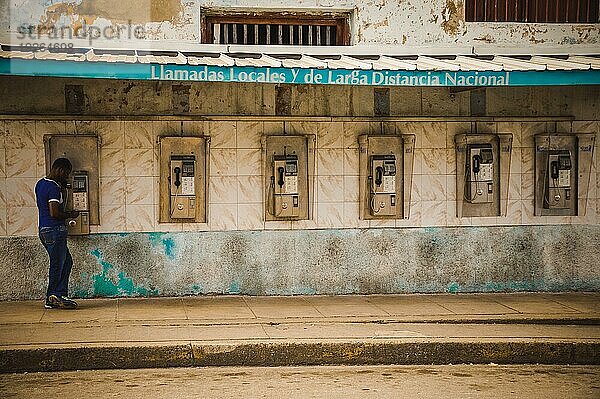 KUBA im Dezember 2015: Eine männliche Person benutzt ein öffentliches Münztelefon  um einen Anruf zu tätigen. Öffentliche Telefone sind für viele Menschen in Kuba die einzigen Telefone  Auslandsgespräche sind teuer