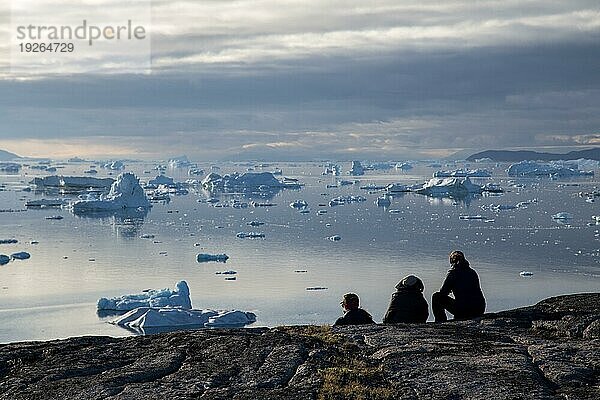 Rodebay  Grönland  Juli 09  2018: Eine Gruppe von Menschen sitzt und schaut sich Eisberge an. Rodebay  auch bekannt als Oqaatsut  ist eine Fischersiedlung nördlich von Ilulissat  Nordamerika