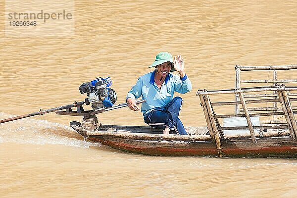 Nicht identifizierter lokaler Fischer in seinem Boot winkt fröhlich auf dem Mekongfluss  Mekongdelta Vietnam