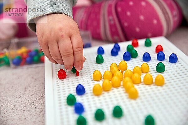 Kleinkind spielt mit bunten Stiften