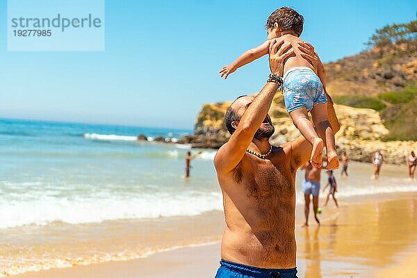 Vater spielt im Sand und hat Spaß mit seinem Sohn  Strand Praia do Barranco das Belharucas  Albufeira  Algarve. Portugal