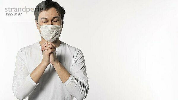 Vorderansicht kranker Mann mit medizinischer Maske beim Beten