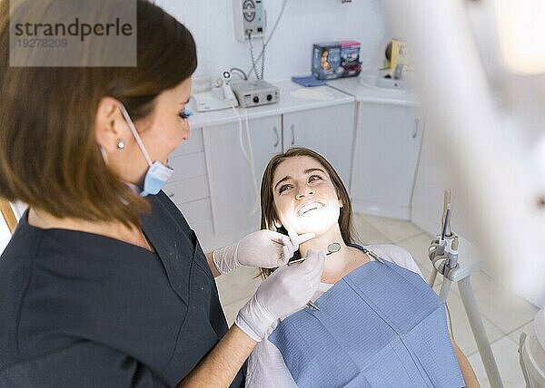 Schöne lächelnde junge Frau bei einer zahnärztlichen Untersuchung