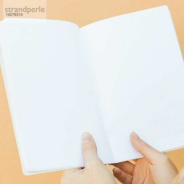 Close up Hände halten leere weiße Buch gegen farbigen Hintergrund