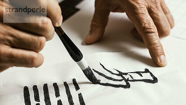 Close up Mann schreibt chinesische Symbole weißes Papier
