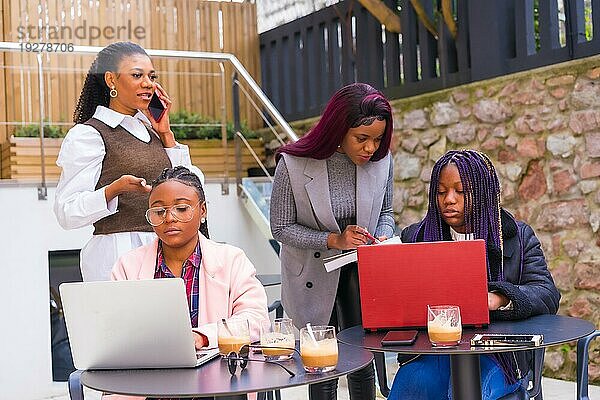 Junge Geschäftsfrauen schwarzer Ethnie. Bei einer Geschäftsbesprechung in einer Cafeteria mit Computern und Kaffee auf dem Tisch. Teamarbeit
