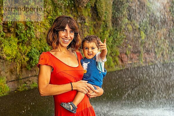 Eine Mutter mit ihrem Sohn in einem roten Kleid am Anjos Wasserfall  Madeira  hat Spaß