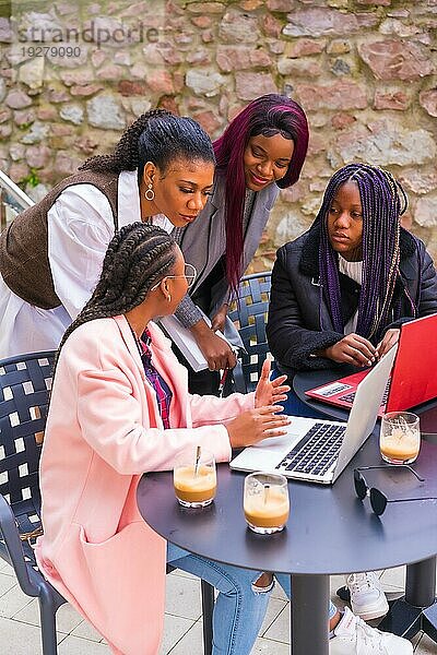 Junge Geschäftsfrauen schwarzer Ethnie. In einer Teamwork Sitzung  in einer Cafeteria mit Computern und Notizen
