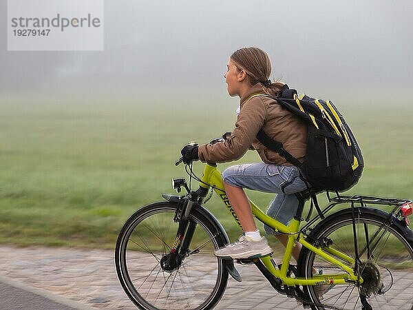 Junge mit Fahrrad und Schulmappe durch den Nebel  Morgennebel an den Wiesen