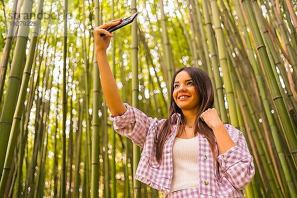 Junges kaukasisches Mädchen mit einem rosa Rock in einem Bambuswald. Genießen Sie den Sommerurlaub in einem tropischen Klima  Lebensstil eines Mädchens tun ein Selfie lächelnd im Wald