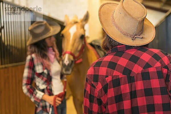 Zwei Cowgirl Frauen  die ein Pferd streicheln  mit südamerikanischem Outfit  Lebensstil von zwei Frauen  die in einem Stall arbeiten