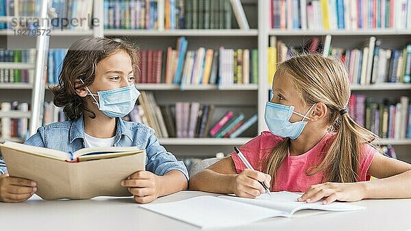 Kinder machen ihre Hausaufgaben mit einer medizinischen Maske
