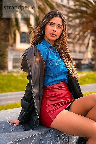 Lifestyle in der Stadt  eine hübsche brünette Kaukasierin in Jeanshemd  Baskenmütze und rotem kurzen Rock genießt die Sommerferien