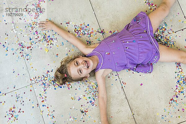 Overhead Ansicht glücklich niedlichen Mädchen liegen mit Konfetti Boden