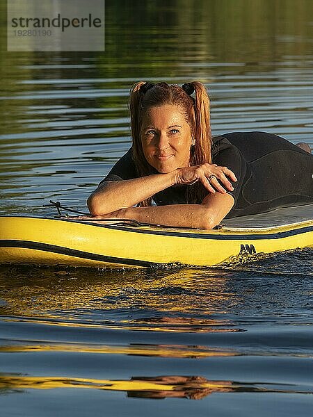 Frau liegt entspannt auf standup paddle board im See  Deutschland  Europa