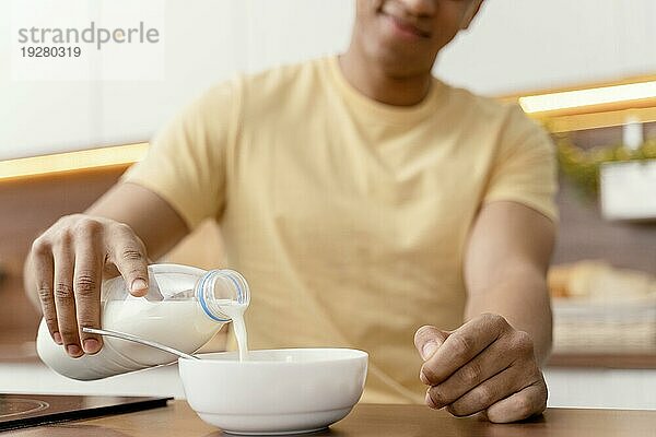 Porträt Mann zu Hause gießt Milch Schüssel