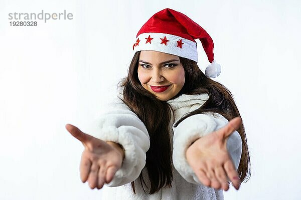 Hübsches lateinisches Mädchen in Weihnachten mit einem weißen Hintergrund  trägt eine Weihnachtsmütze mit Sternen  mit offenen Armen feiern Weihnachten im Winter