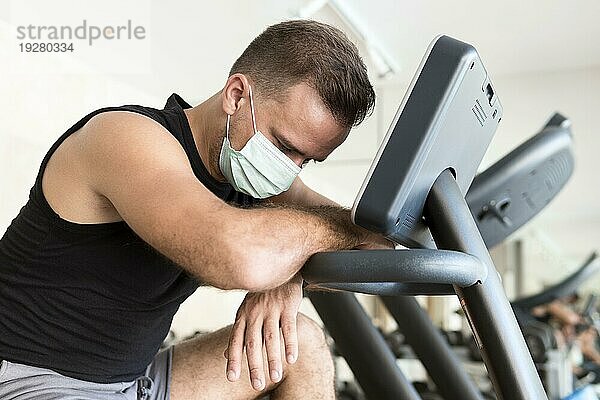 Seitenansicht erschöpft Mann mit medizinischer Maske Fitnessstudio