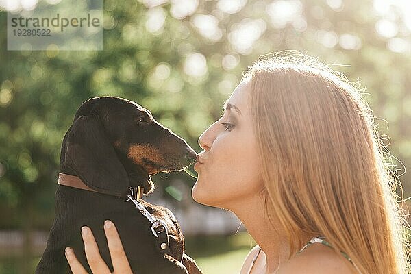 Seitenansicht schöne junge Frau küsst ihren Hund