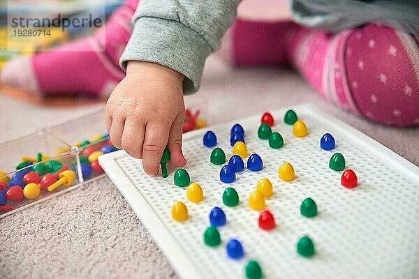 Kleinkind spielt mit bunten Stiften