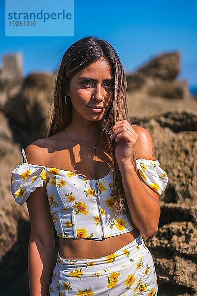 Porträt einer jungen Frau in einem weißen Kleid am Strand  am Meer  die den Sommer mit einem verführerischen Blick genießt