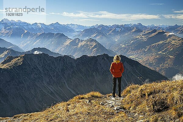 Eine Wanderin steht auf dem Nebelhorn und schaut auf die Alpen. Gutes Wetter mit blauem Himmel  Herbst. Nebelhorn  Oberstdorf  Allgäuer Alpen  Bayern  Deutschland  Europa