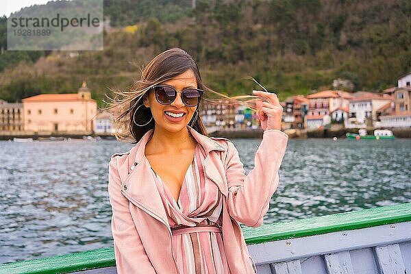 Hübsche lateinische Frau mit Sonnenbrille beim Sightseeing auf einem Boot entlang der Küste. Sommertourismus im Urlaub  Modell mit Spaß auf Ausflug