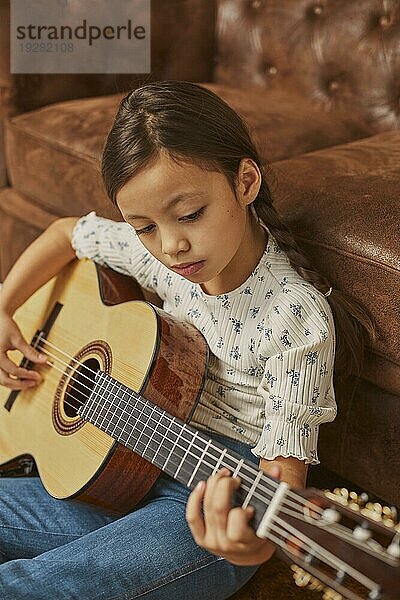 Kleines Mädchen spielt Gitarre zu Hause