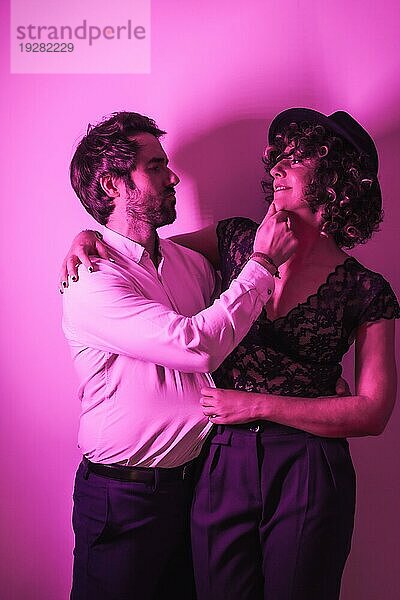 Studio Lifestyle  ein junges  verliebtes Paar  das sich am Valentinstag umarmt  beleuchtet von einem rosa Neonlicht