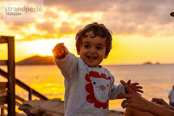Lachender Junge bei Sonnenuntergang am Strand von Cala Comte auf der Insel Ibiza. Balearen