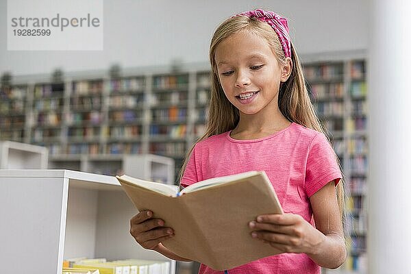 Kleines Mädchen liest Buch Bibliothek