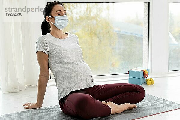 Schwangere Frau mit medizinischer Maske beim Entspannen