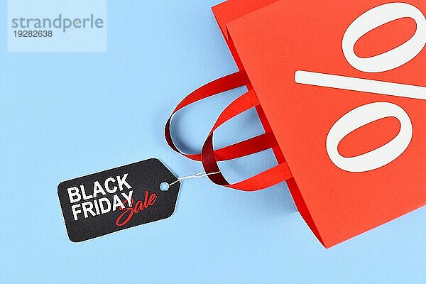 Rote Einkaufstasche mit Tag mit Black Friday Verkauf Tag auf blauem Hintergrund
