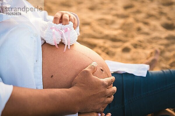 Silhouette einer schwangeren Frau in einem weißen Kleid am Strand sitzend  schwanger Sitzung einer neuen Schwangerschaft