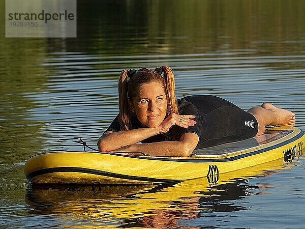 Frau liegt entspannt auf standup paddle board im See  Deutschland  Europa