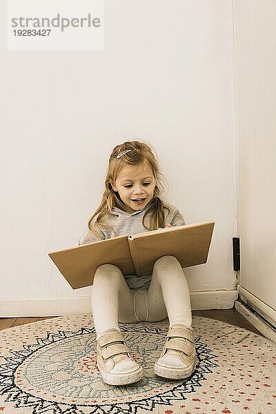 Fröhliches Mädchen liest an der Wand