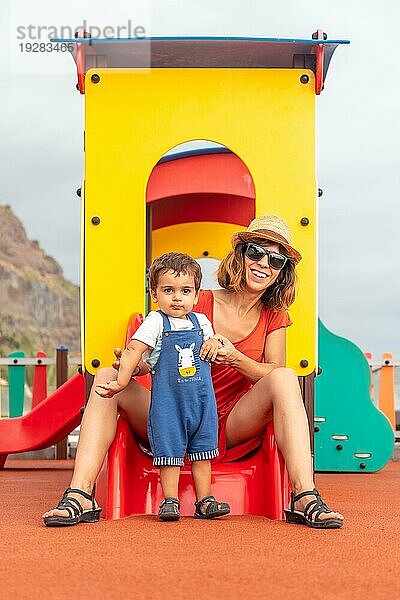 Baby spielt auf einem Spielplatz und hat Spaß im Sommer  mit seiner Mutter