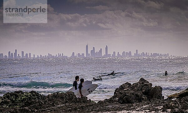 Surfers Paradise  Australien am 16. August 2016: Surfer genießen die Wellen bei Snapper Rocks mit der Skyline von Surfers Paradise im Hintergrund